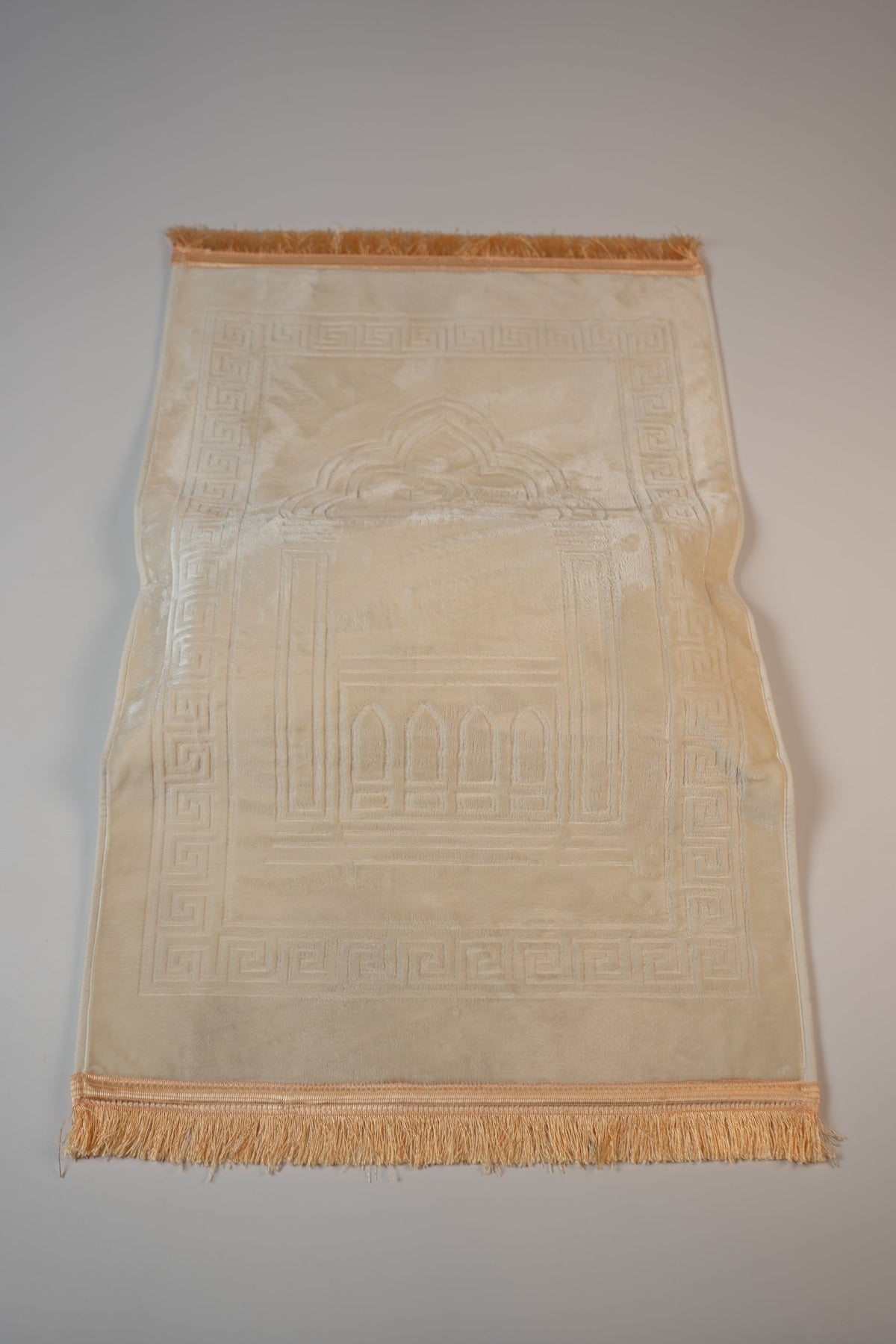 Ergonomic prayer mat in Beige, top view with embossed mihrab design