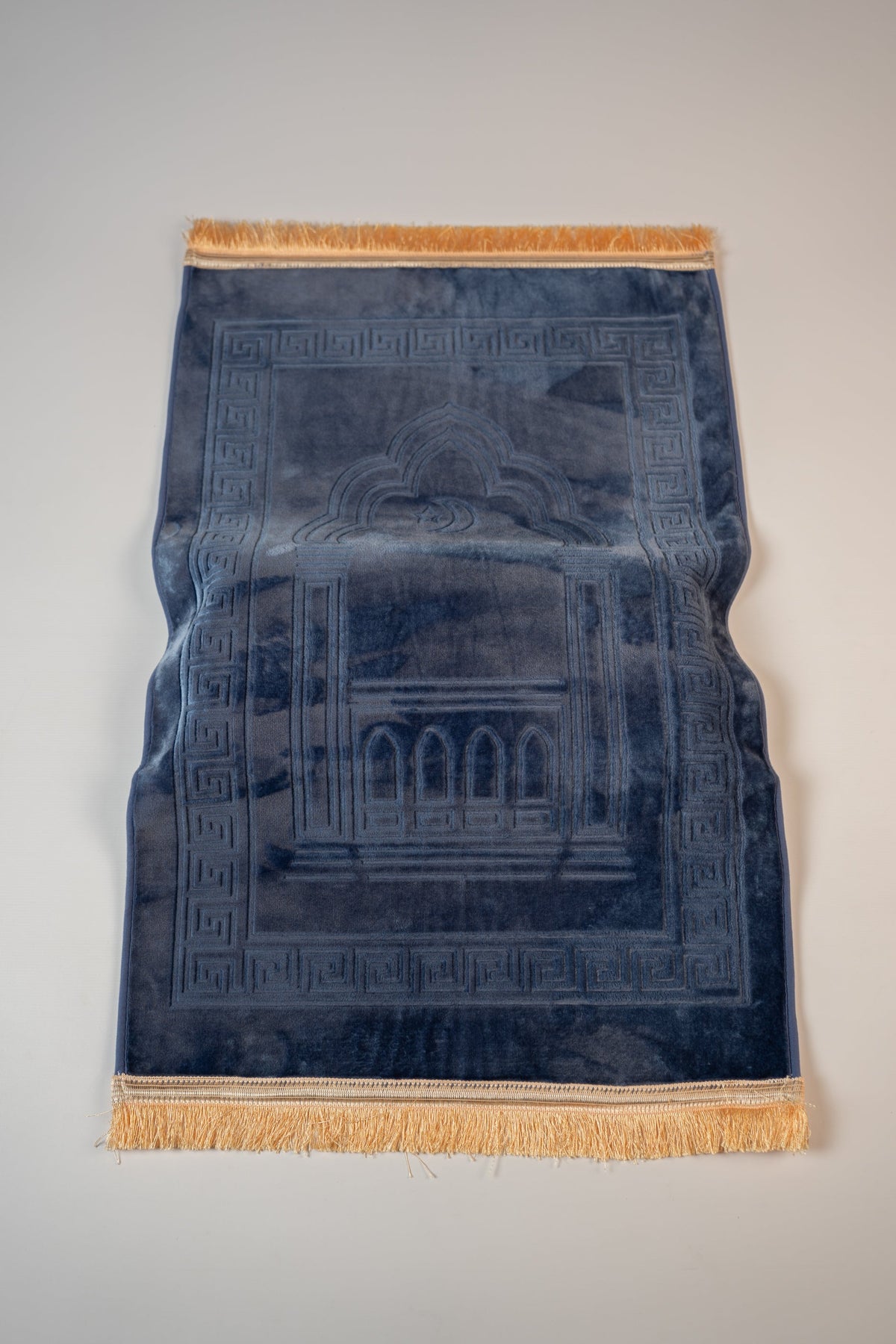 Ergonomic prayer mat in Navy Blue, top view with embossed mihrab design